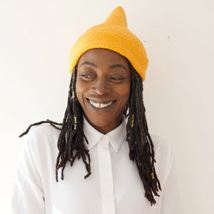 Model wearing hand knitted gold coloured woolen hat